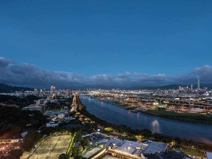 A cityscape at dusk with a river, bridges, and a prominent tower.