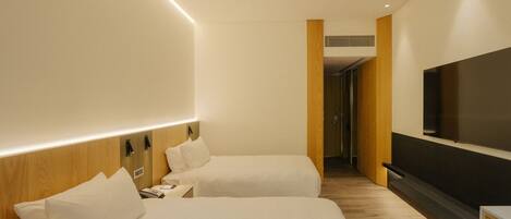 A hotel room with two beds, a TV, and a wooden accent wall.