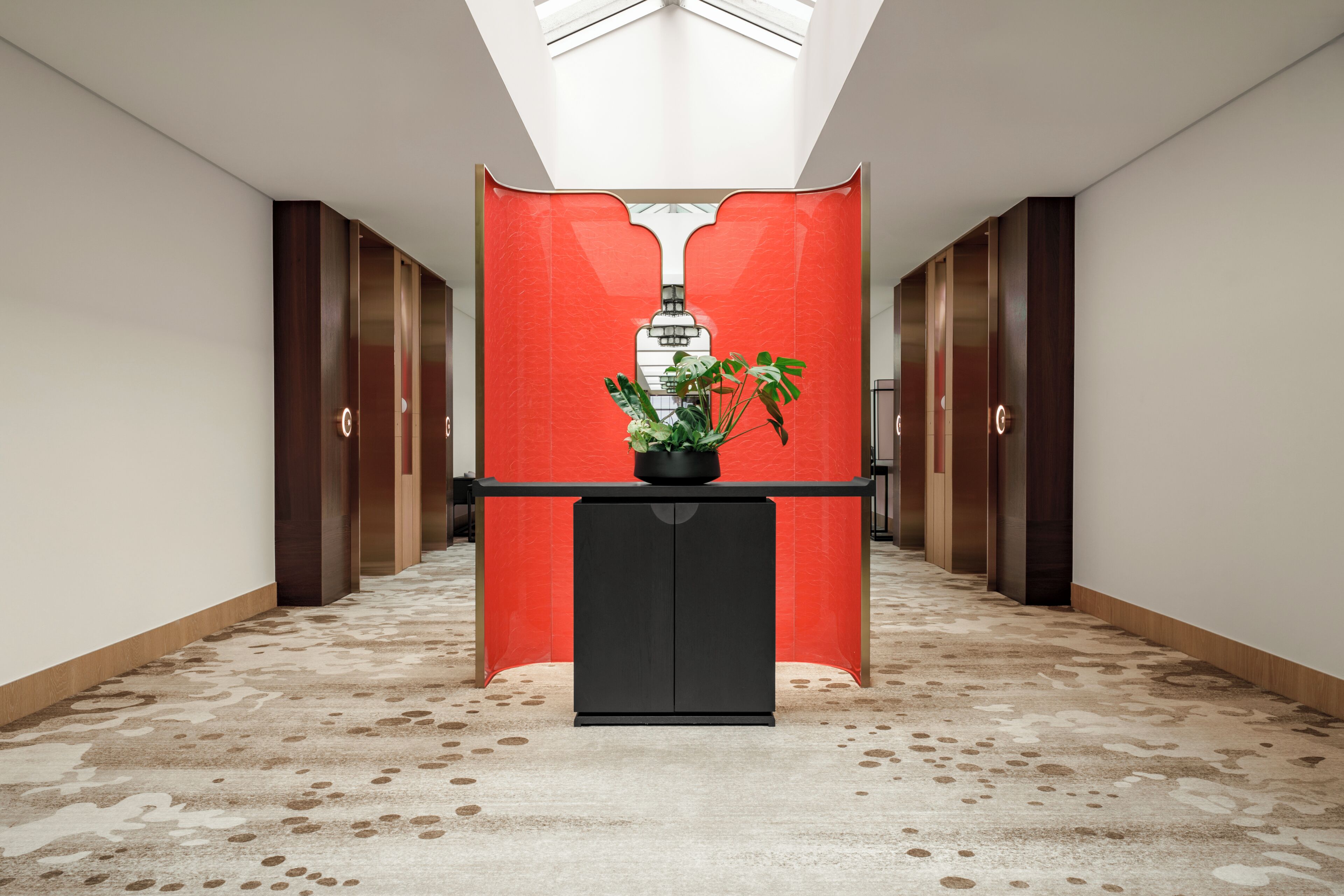 A hallway with a reception desk, a red partition, and a skylight.
