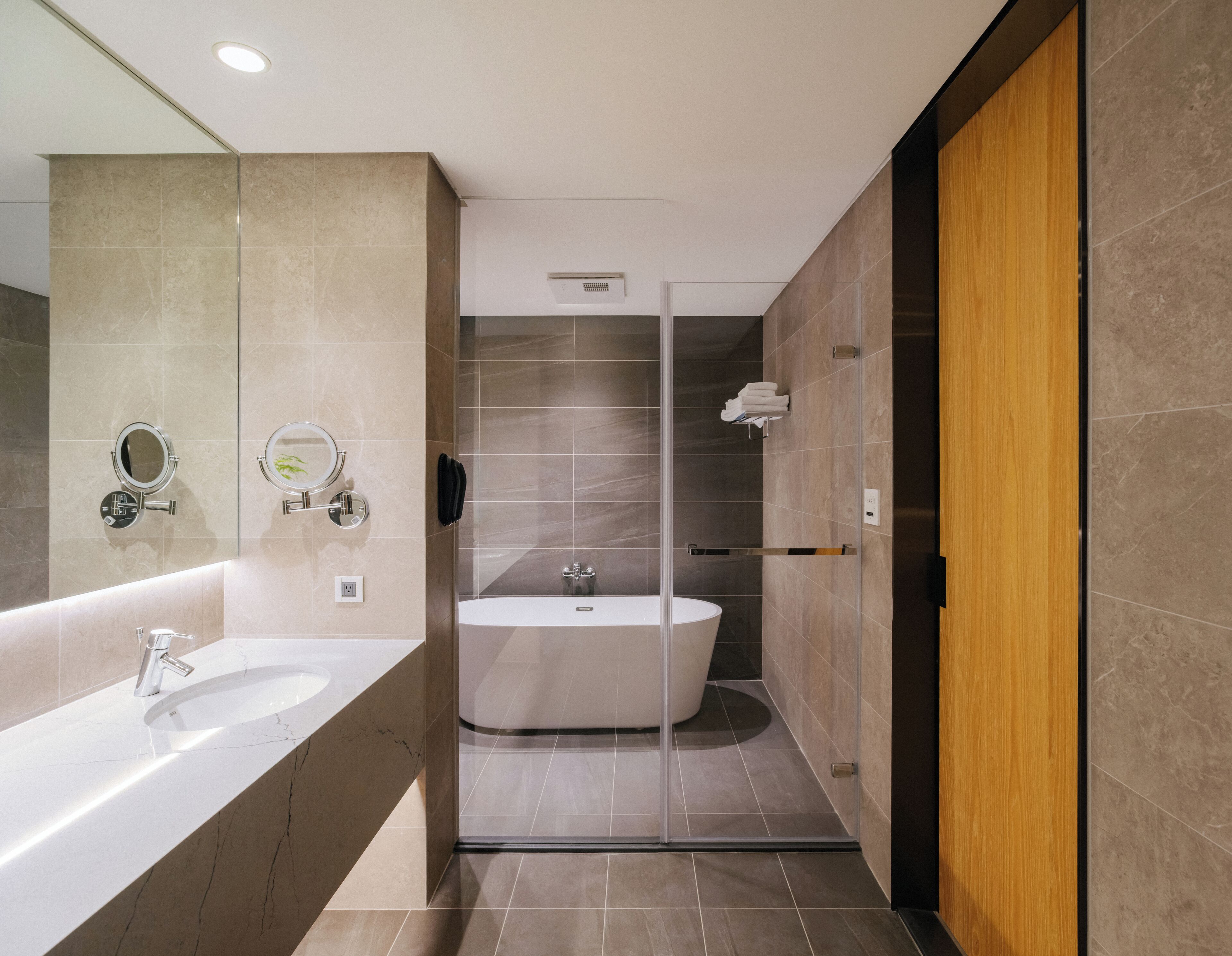 A modern bathroom with a large bathtub, a double sink, and a glass shower enclosure.