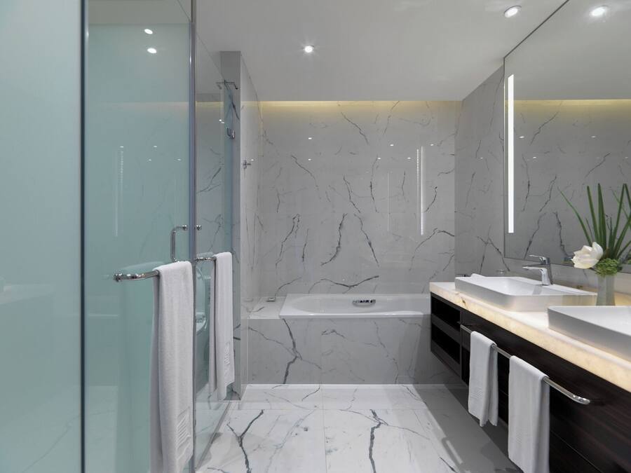 Ein modernes Badezimmer mit Duschkabine aus Glas, freistehender Badewanne und Waschtisch mit Spüle und Spiegel.