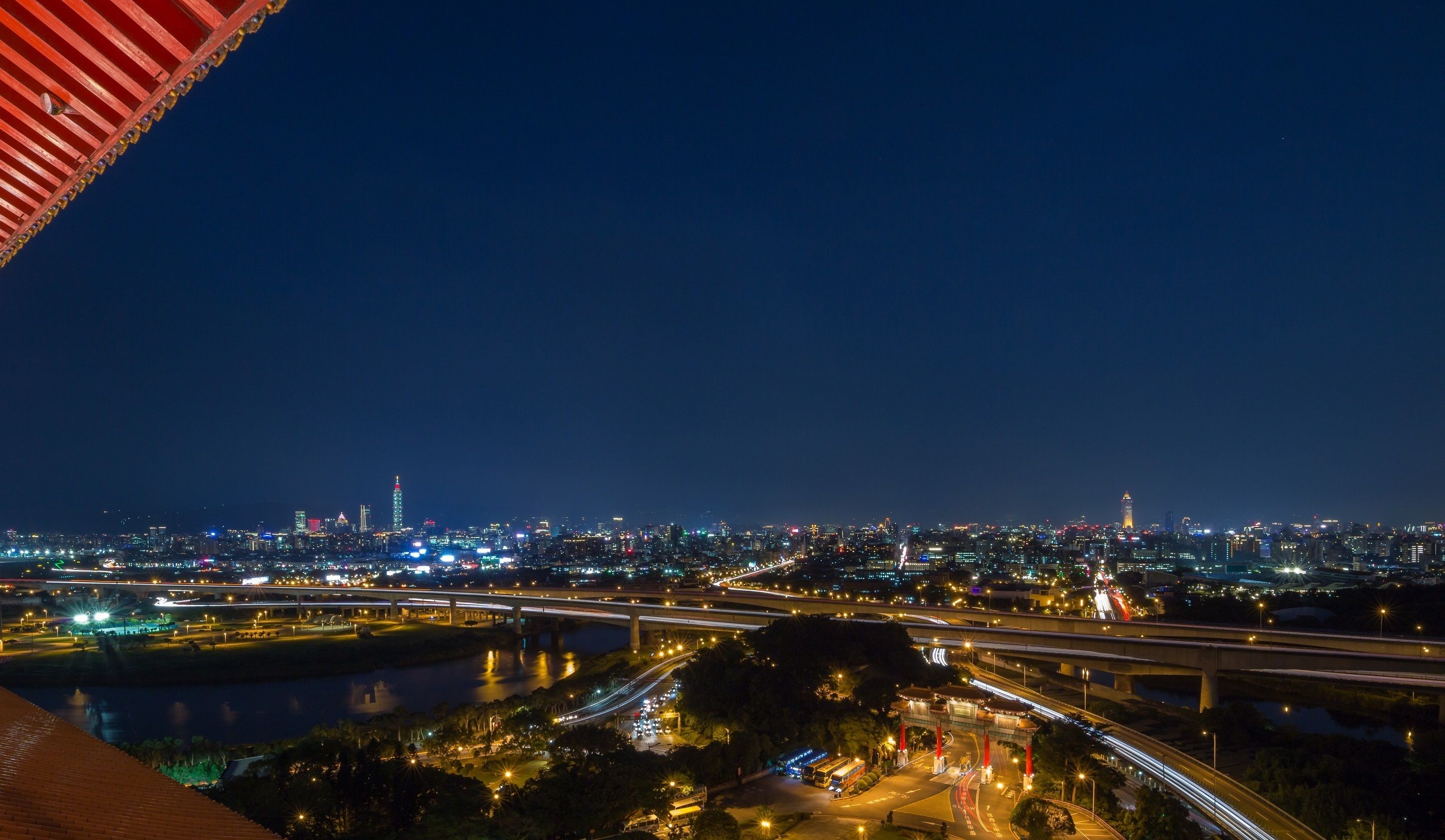 A nighttime cityscape with illuminated buildings, a river, and multiple highways.