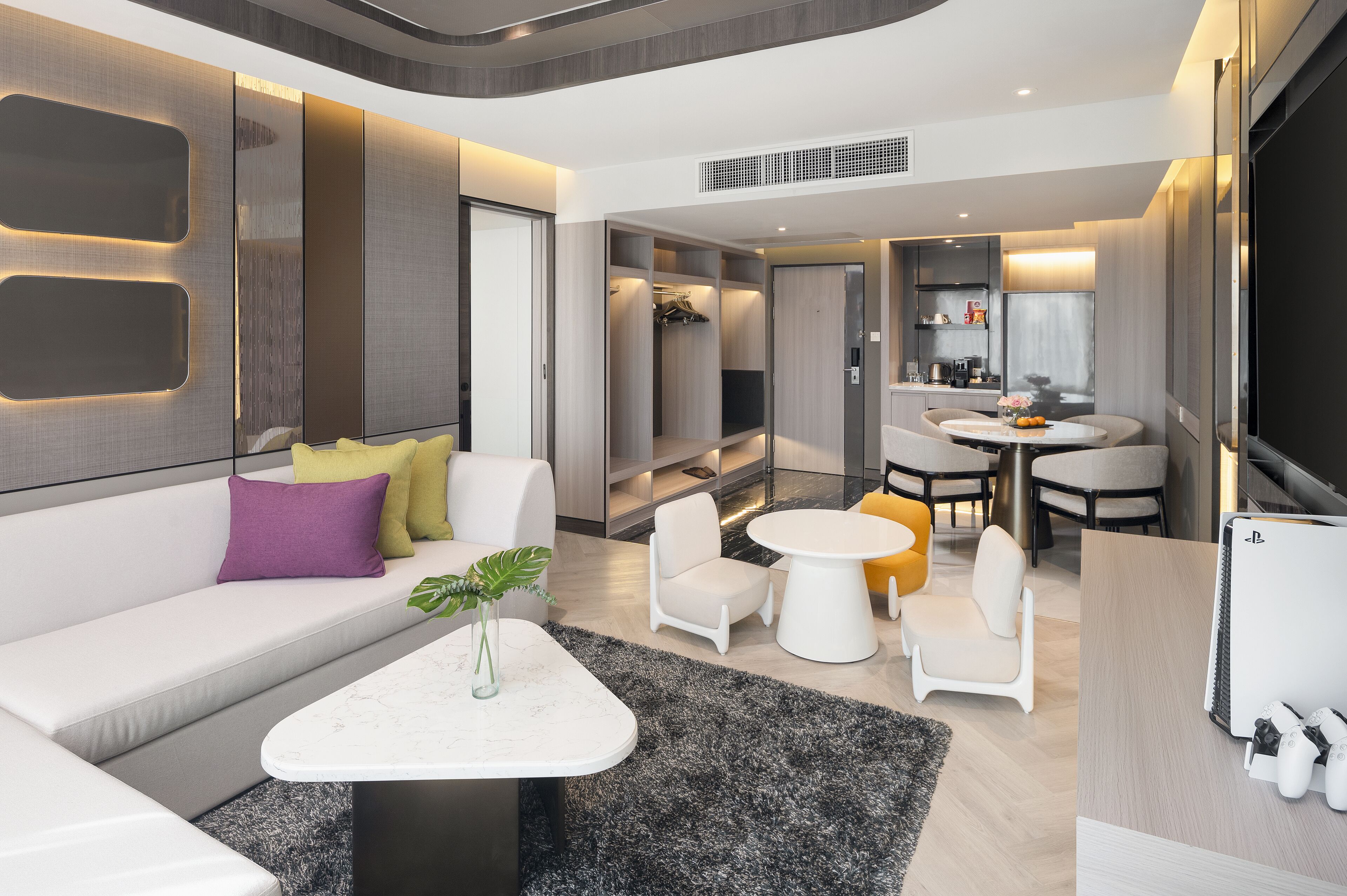 Una sala de estar moderna con sofá, mesa de centro y sillas. Hay un comedor con mesa y sillas. La habitación tiene un ventanal grande y un armario empotrado.