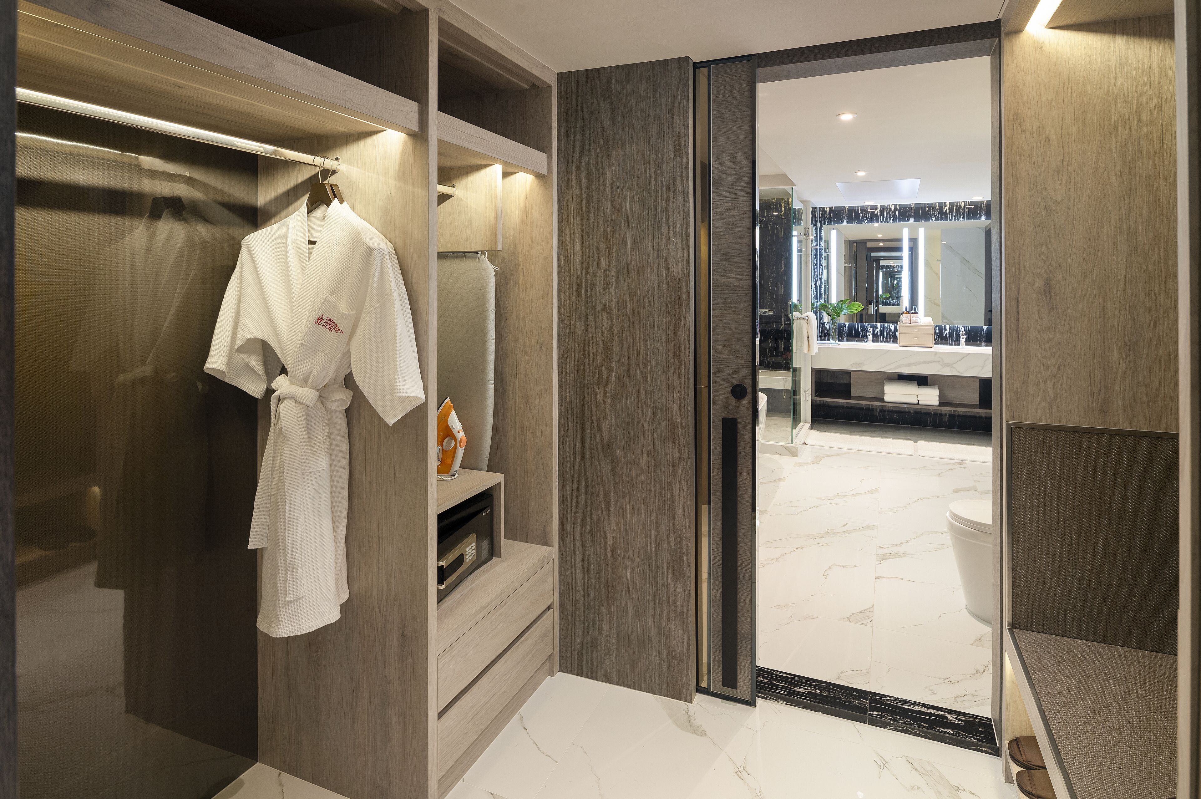 A modern bathroom with a marble floor, a large mirror, and a wooden vanity.