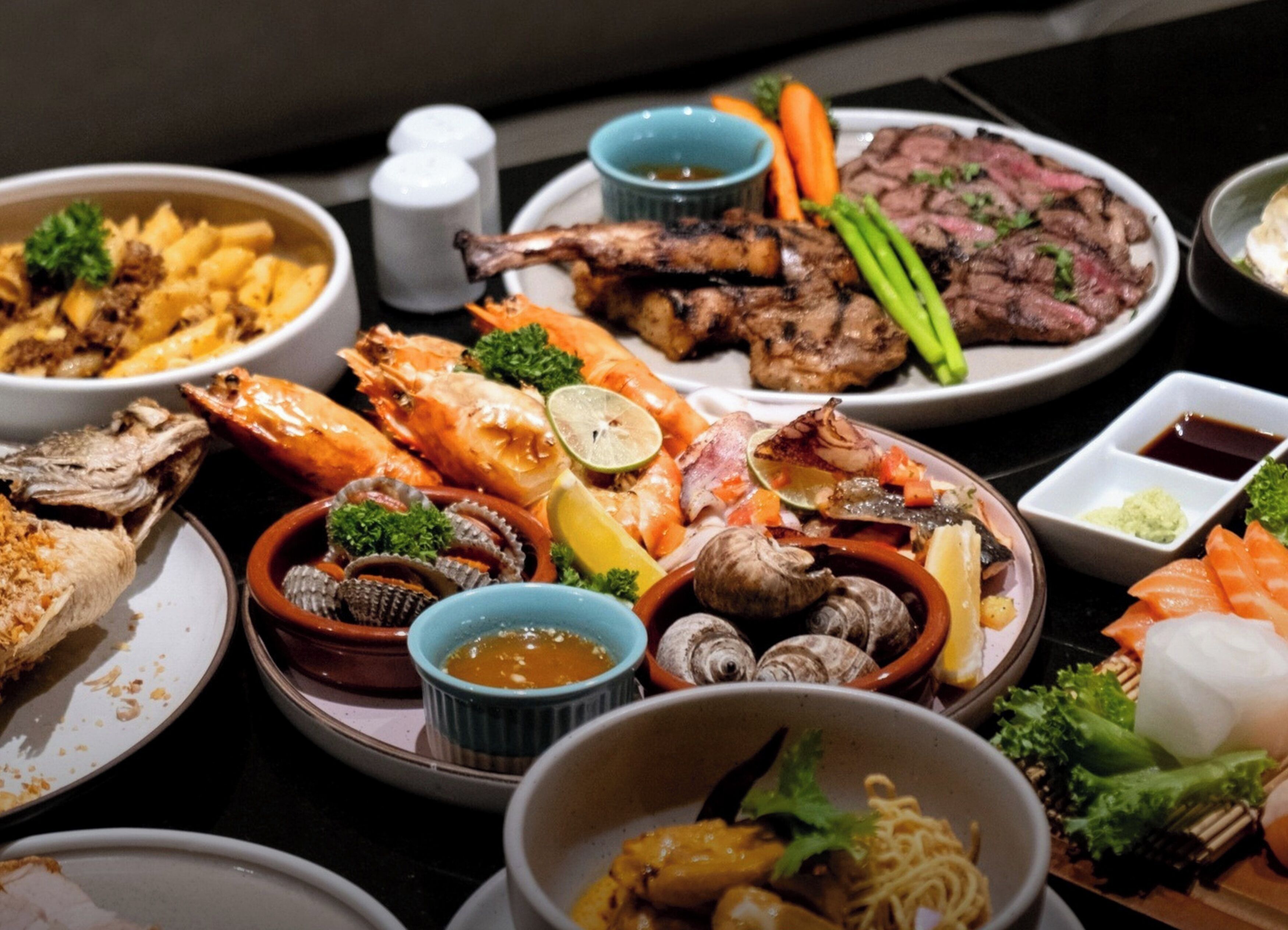 A variety of seafood dishes including shrimp, mussels, and oysters, served on a table with multiple small bowls and plates.
