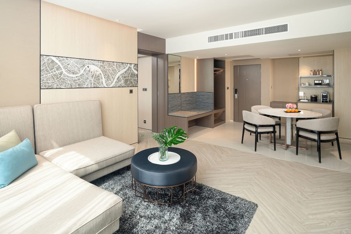A modern living room with a sofa, a round coffee table with a plant, and a dining area with chairs and a table.