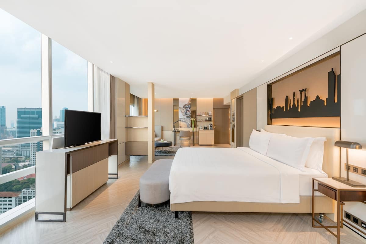 A modern hotel room with a large bed, a flat-screen TV, a desk, and a city view.