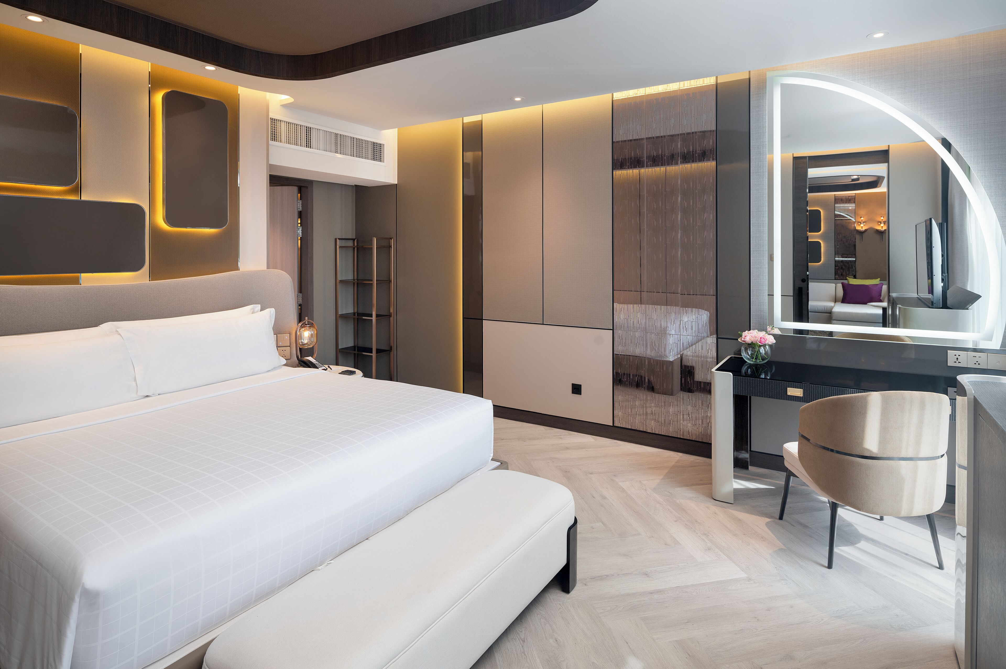 Una habitación de hotel moderna con una cama grande, un tocador con espejo y un escritorio con silla.