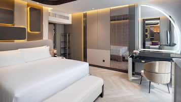 Una habitación de hotel moderna con una cama grande, un tocador con espejo y un escritorio con silla.