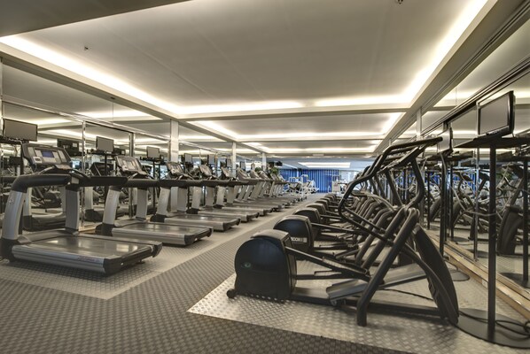 Un gimnasio con cintas de correr y equipo de ejercicio.