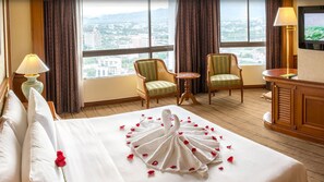 A hotel room with a large bed, two armchairs, a small table, and a TV on the wall. - Centara Riverside Hotel Chiang Mai (Chiang Mai)
