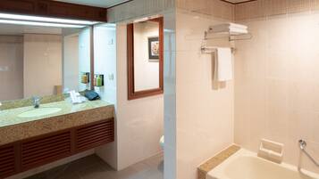 A bathroom with a granite countertop, two sinks, a large mirror, a framed picture, a towel rack, and a bathtub.