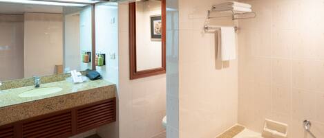 A bathroom with a granite countertop, two sinks, a large mirror, a framed picture, a towel rack, and a bathtub.