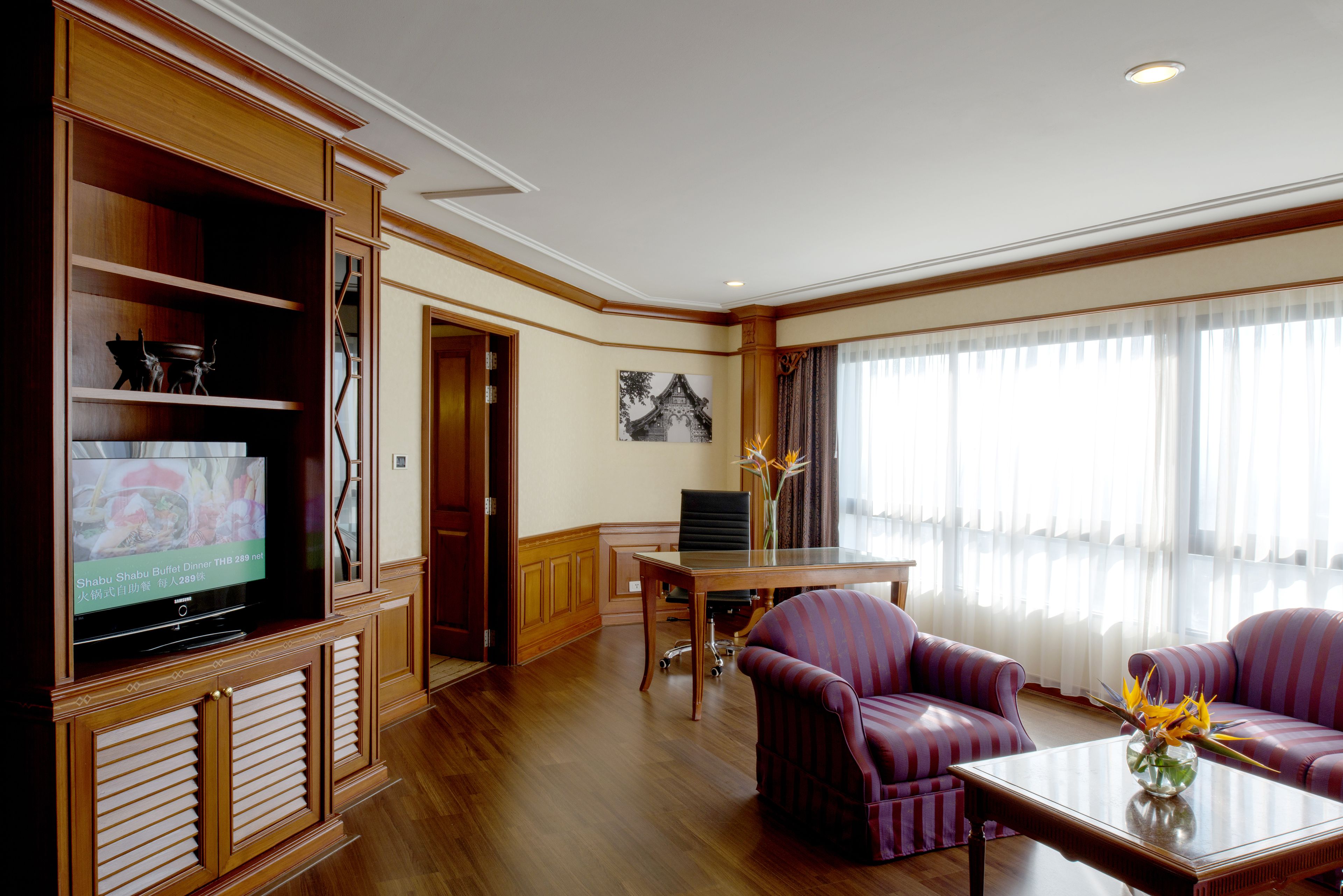 Una sala de estar con televisor, una mesa de comedor y dos sofás.