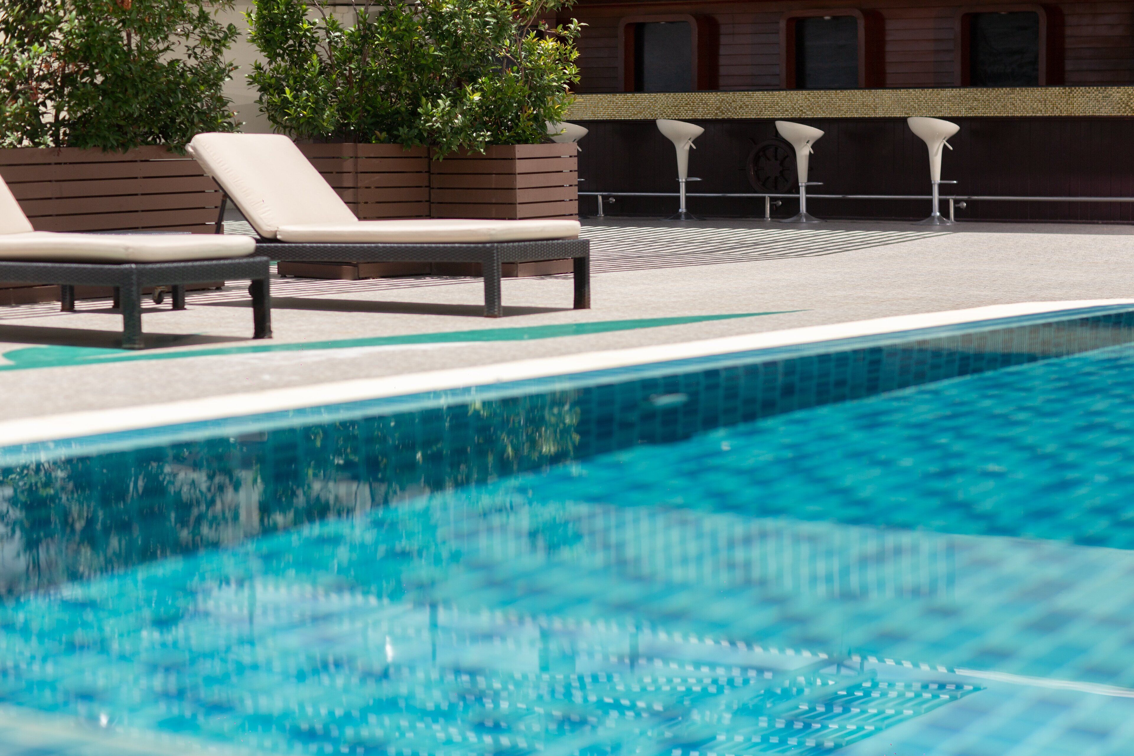 A swimming pool with lounge chairs and a bar area.