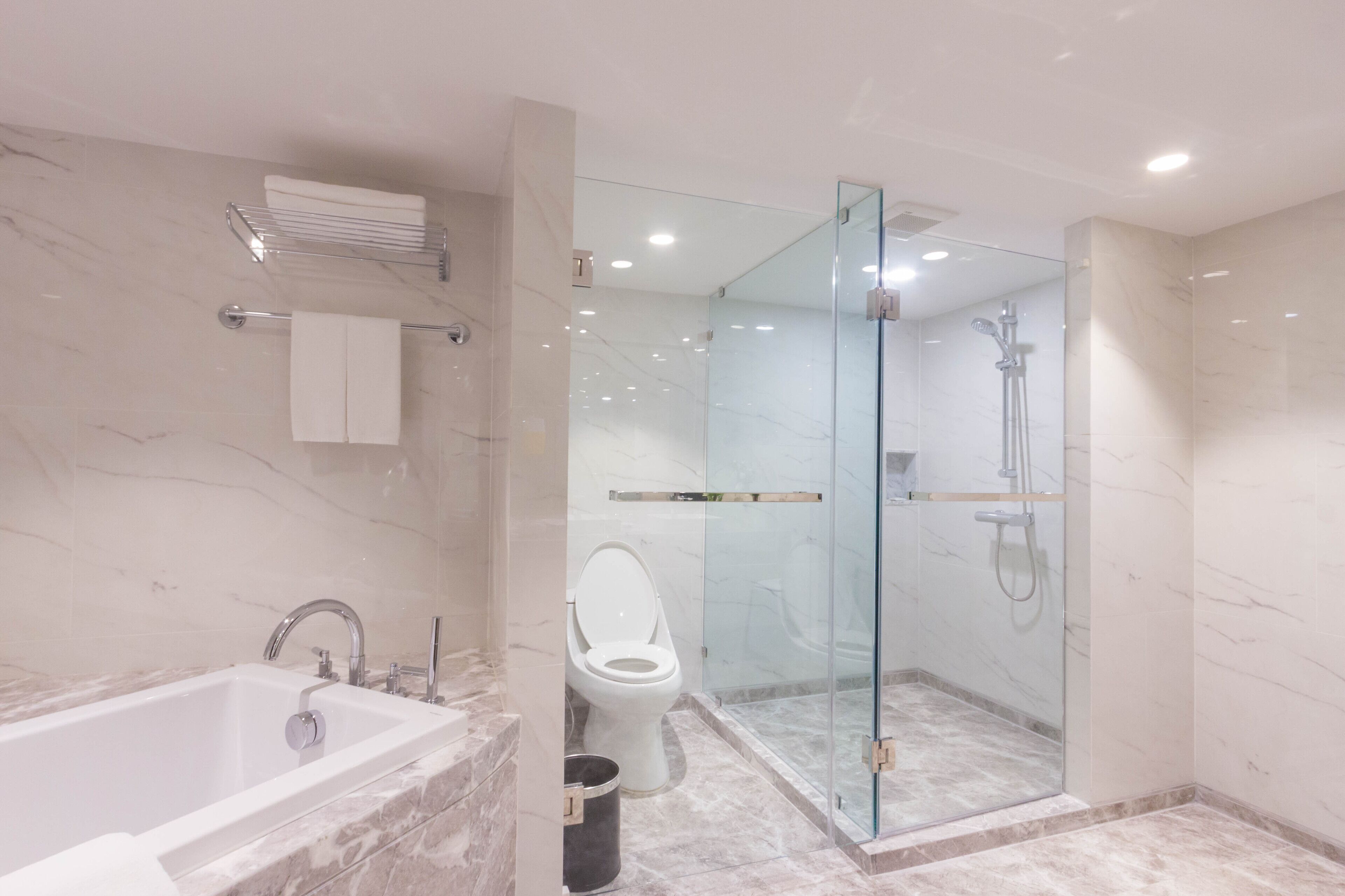 A modern bathroom with a marble sink, toilet, and a glass-enclosed shower area.