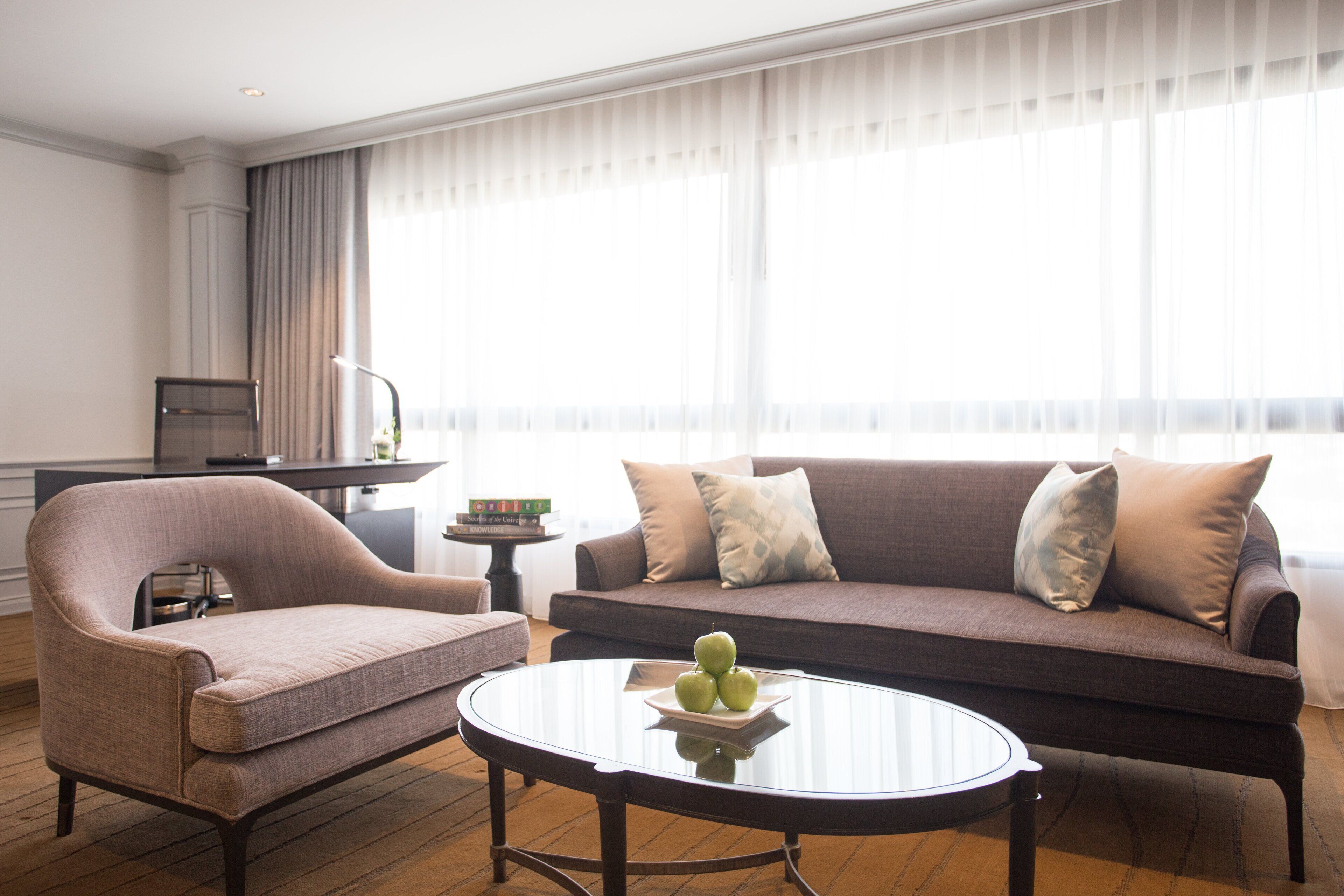 Una sala moderna con un sofá, un sillón y una mesa de centro con manzanas.