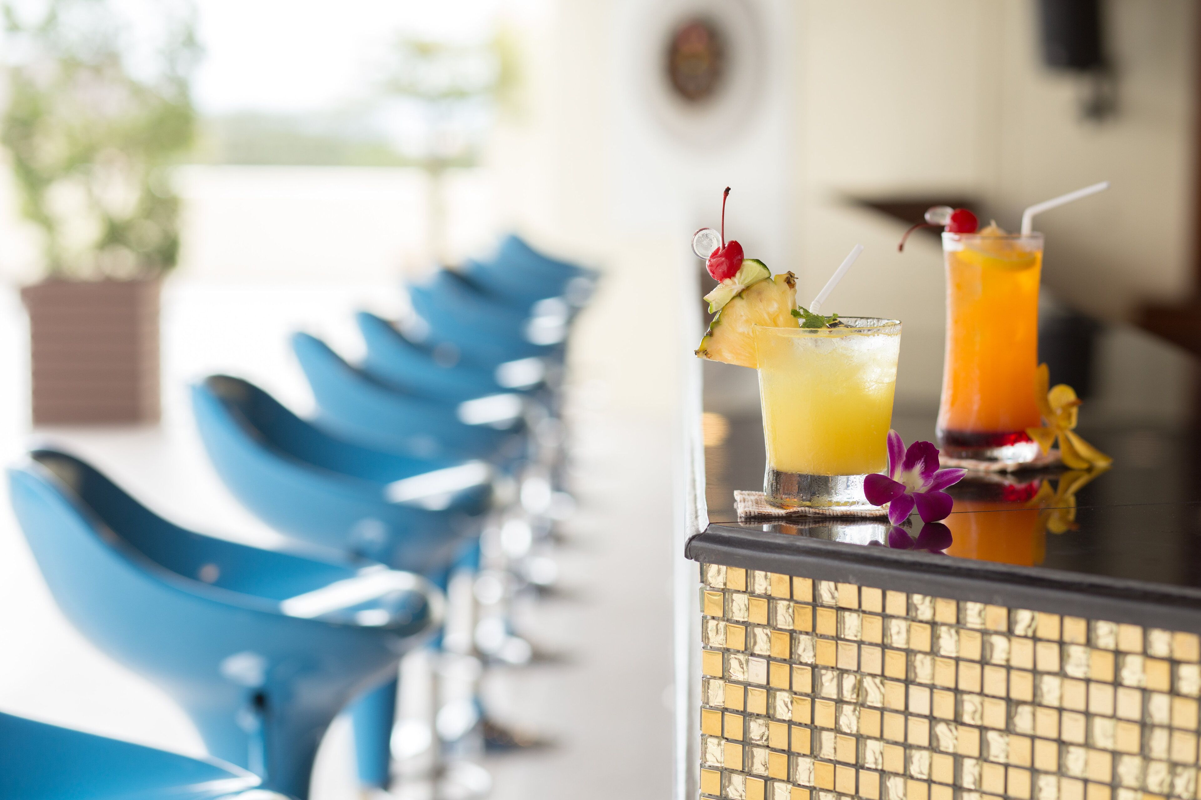 Una zona de bar con sillas azules y dos bebidas adornadas.