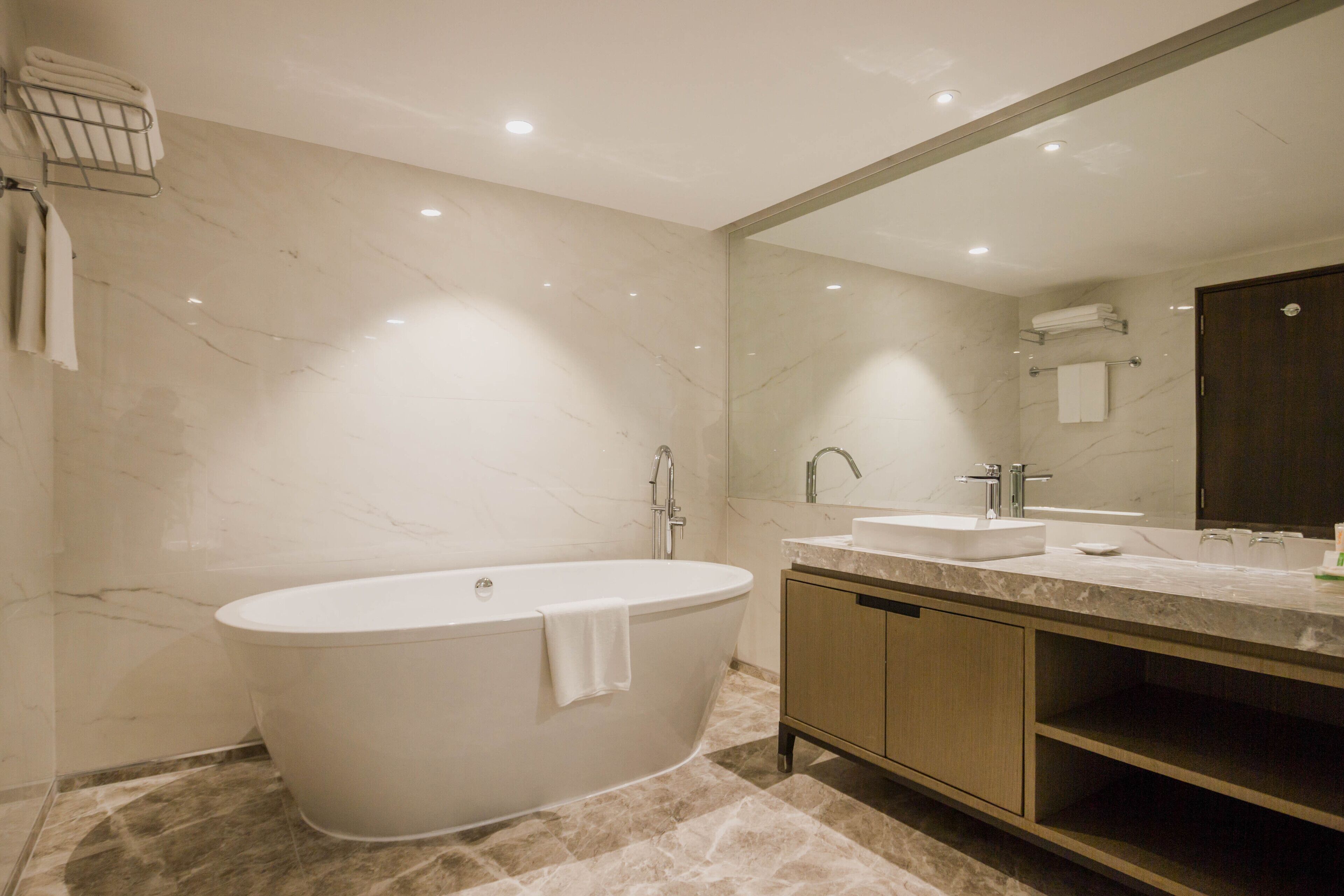 Un baño moderno con una bañera independiente, un tocador con lavamanos y un espejo grande.