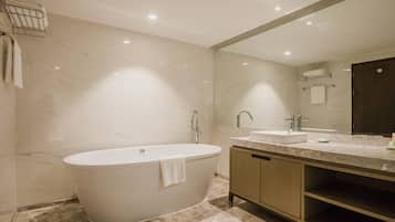 Un baño moderno con una bañera independiente, un tocador con lavamanos y un espejo grande.