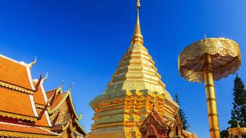 A large, ornate stupa with a pointed top and a golden umbrella-like structure in front.