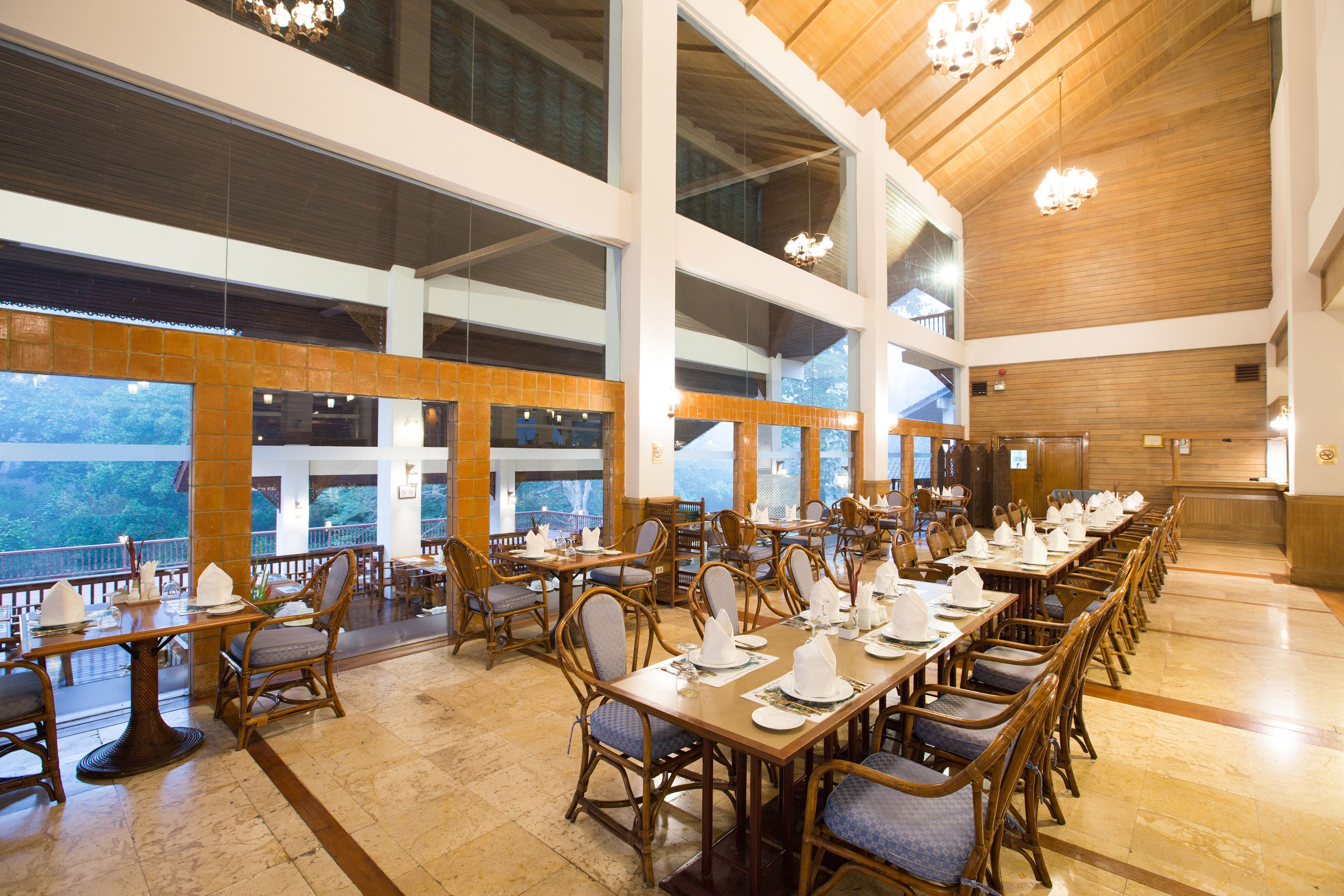 A spacious dining area with high ceilings, large windows, and wooden furniture.
