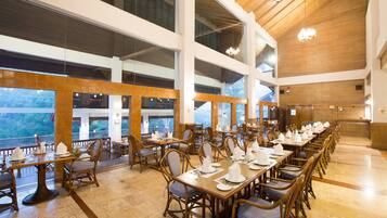 A spacious dining area with high ceilings, large windows, and wooden furniture.