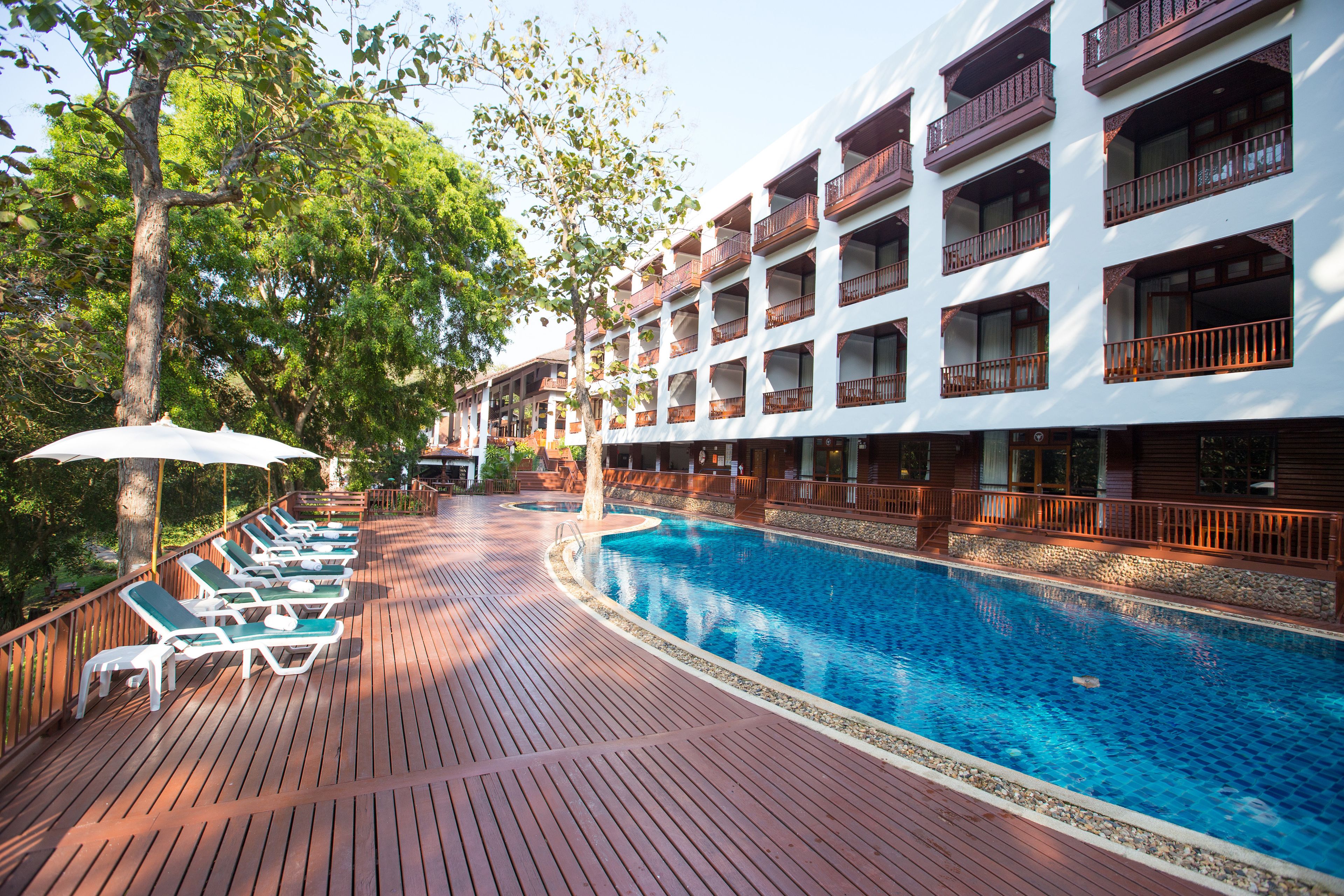 Un espace piscine d’hôtel avec des chaises longues et une terrasse en bois.