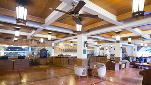 A spacious lobby with a high ceiling, wooden beams, and a central seating area with chairs and a table.
