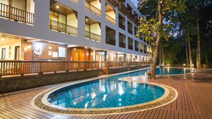 A hotel with a swimming pool, wooden deck, and multiple balconies.