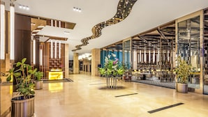 Un moderno vestíbulo de hotel con un mostrador de recepción, zona de estar y plantas decorativas.