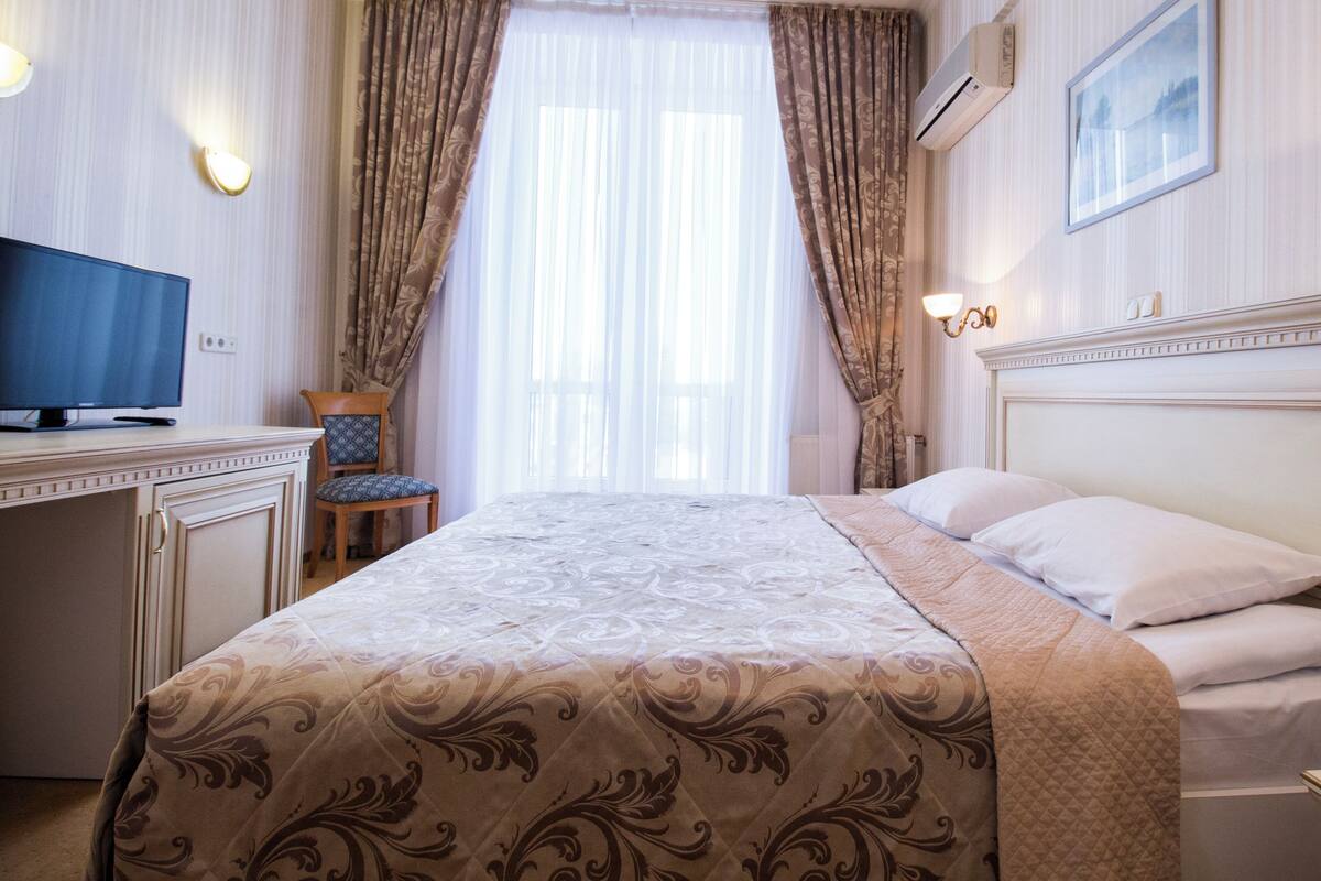 Una habitación de hotel con una cama, un escritorio con televisor y una silla.