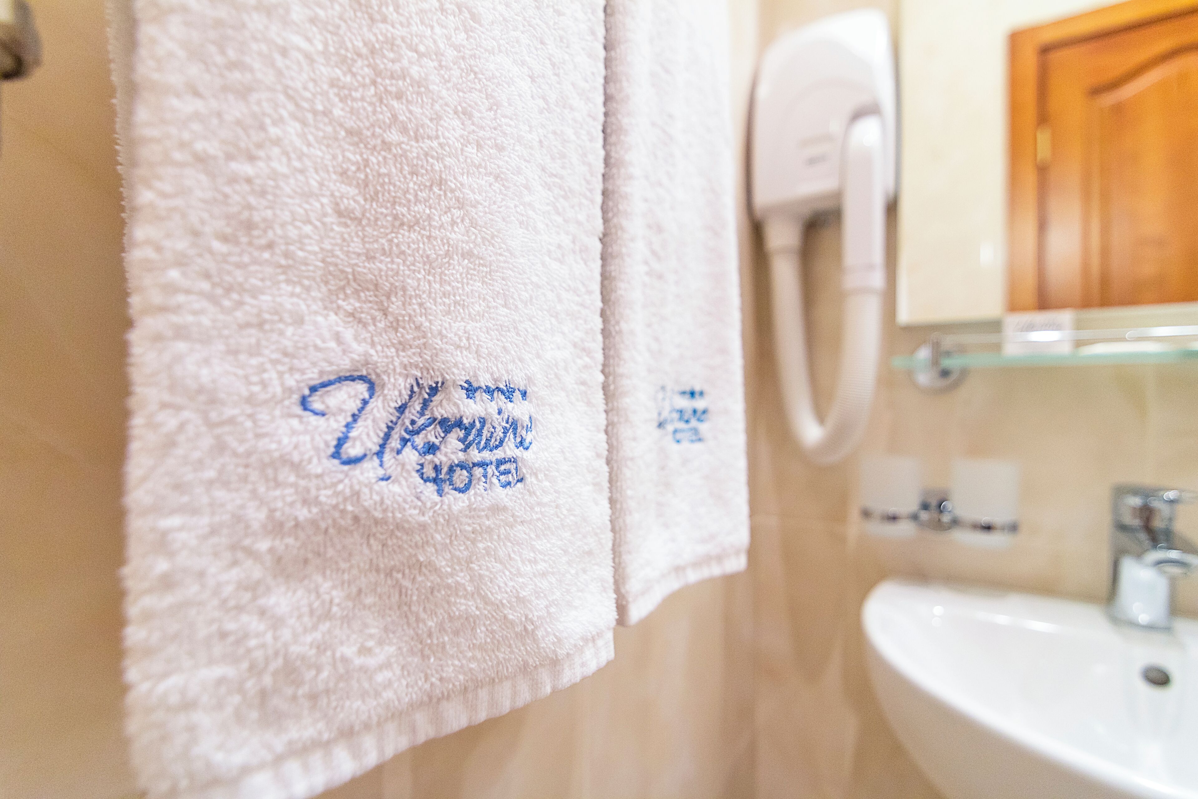 A bathroom with a white sink, a towel rack with a white towel, and a hand dryer.