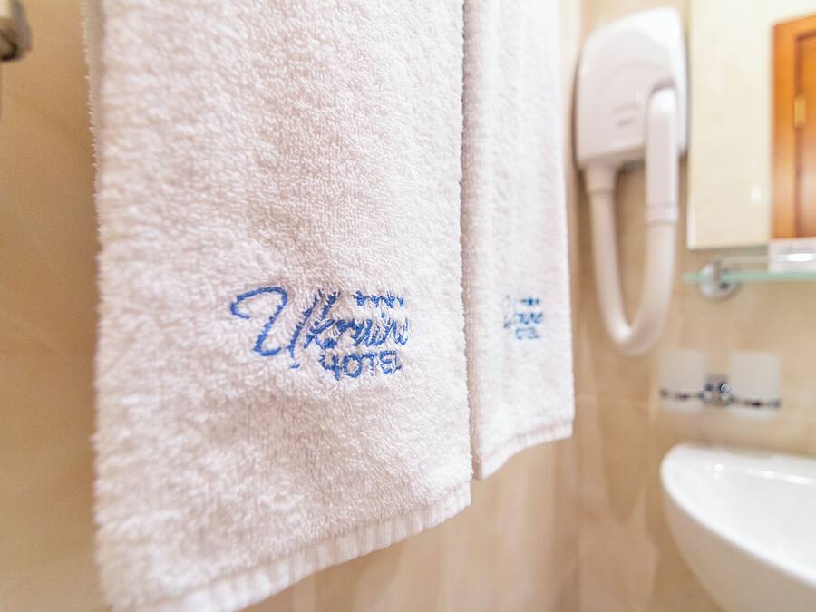 Ein Badezimmer mit einem weißen Waschbecken, einem Handtuchhalter mit einem weißen Handtuch und einem Händetrockner.