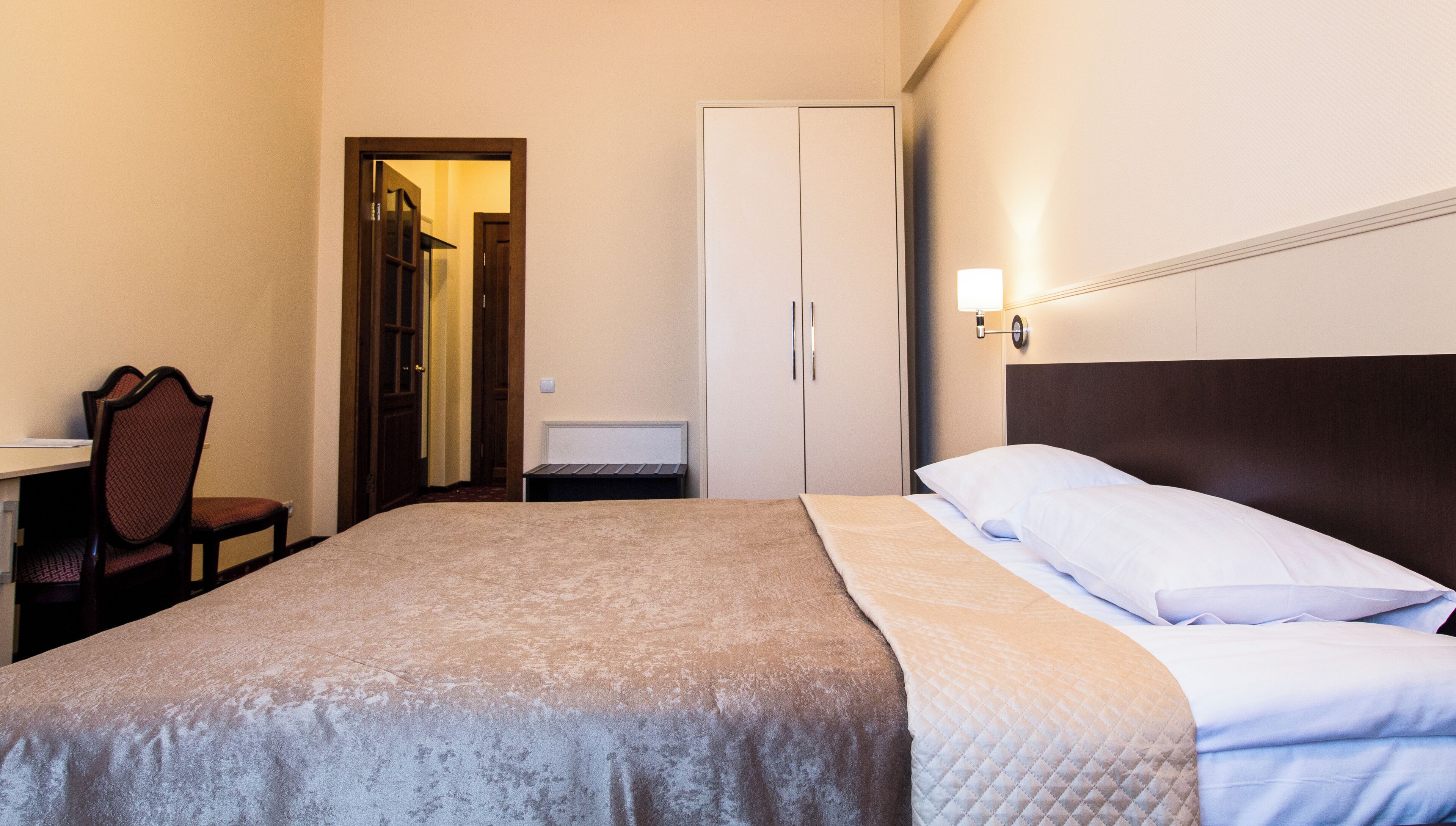 Een hotelkamer met een bed, bureau, stoel en kledingkast.