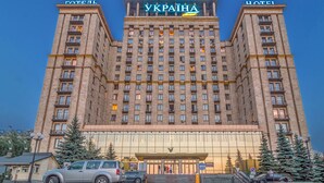 Un gran edificio de hotel con varios pisos, balcones y un letrero llamativo que dice 'UKRAÏNA HOTEL'.