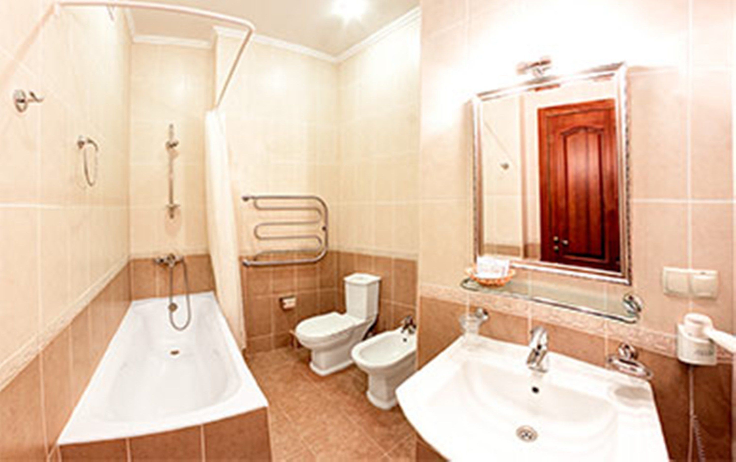 A bathroom with a bathtub, two toilets, a bidet, and a sink.