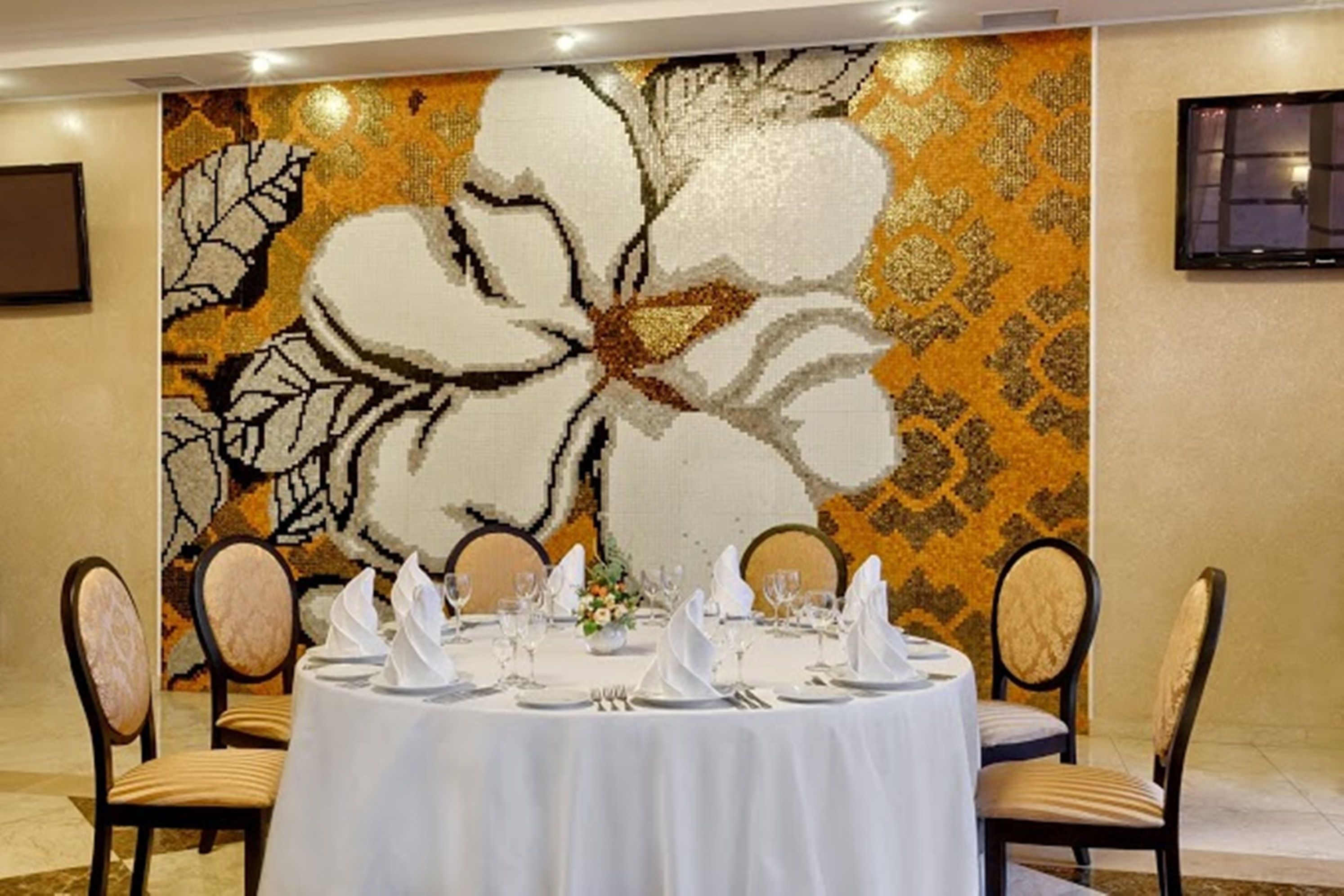 A dining area with a round table set for four, surrounded by upholstered chairs.