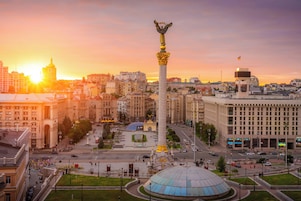 Un paisaje urbano con un monumento destacado, una gran estructura en forma de cúpula y edificios circundantes.