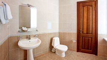 A bathroom with a sink, toilet, and a wooden door.