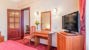A hotel room with a bed, a desk, a chair, a television, and a mirror.