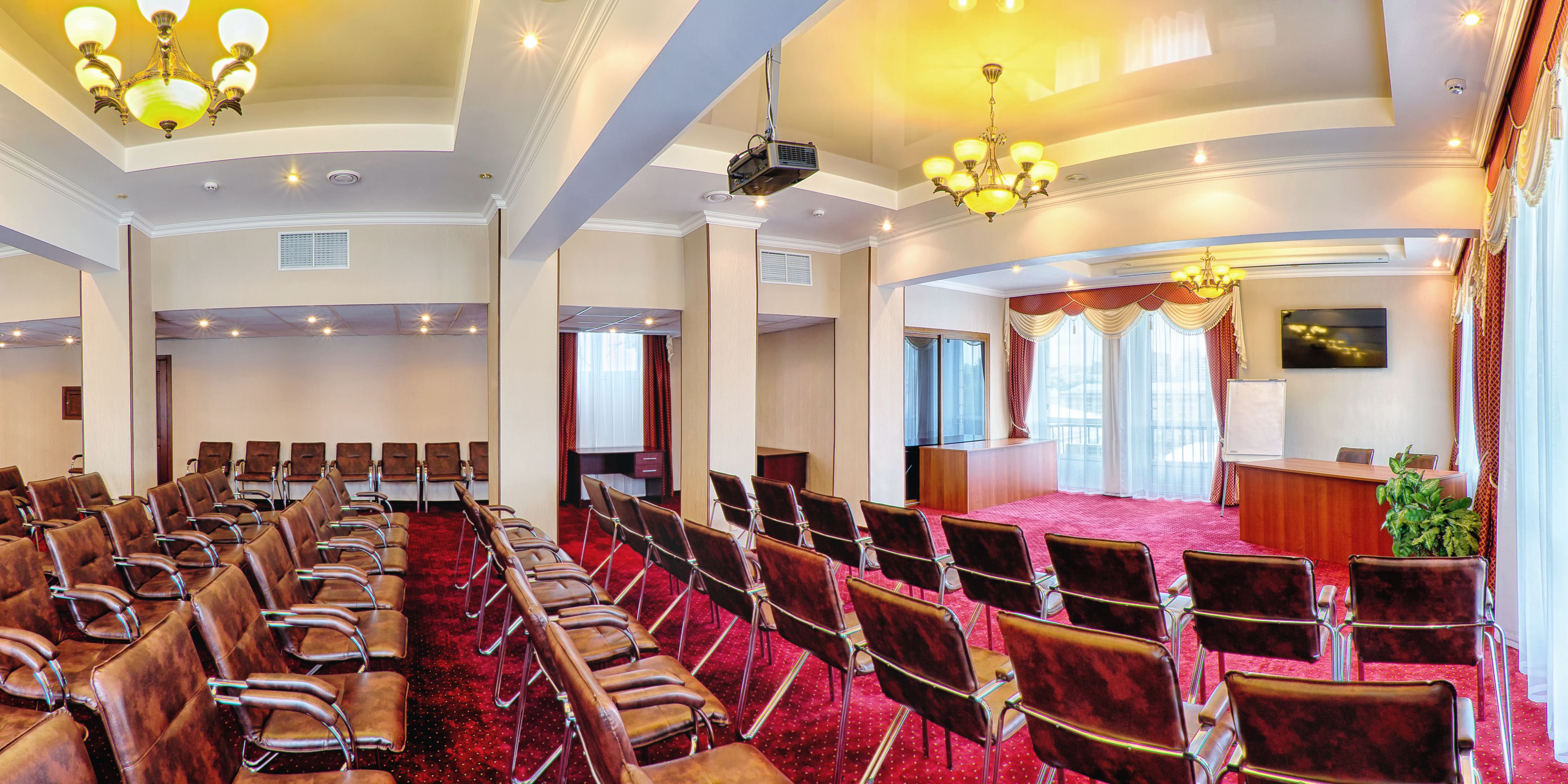 Une salle de conférence avec des rangées de chaises, une scène et un pupitre.