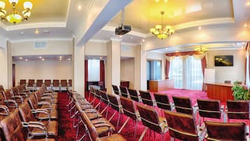Une salle de conférence avec des rangées de chaises, une scène et un pupitre.