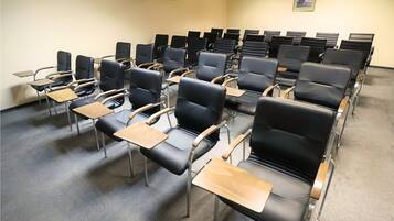 A classroom with rows of black chairs and wooden desks, arranged in a classroom setting.
