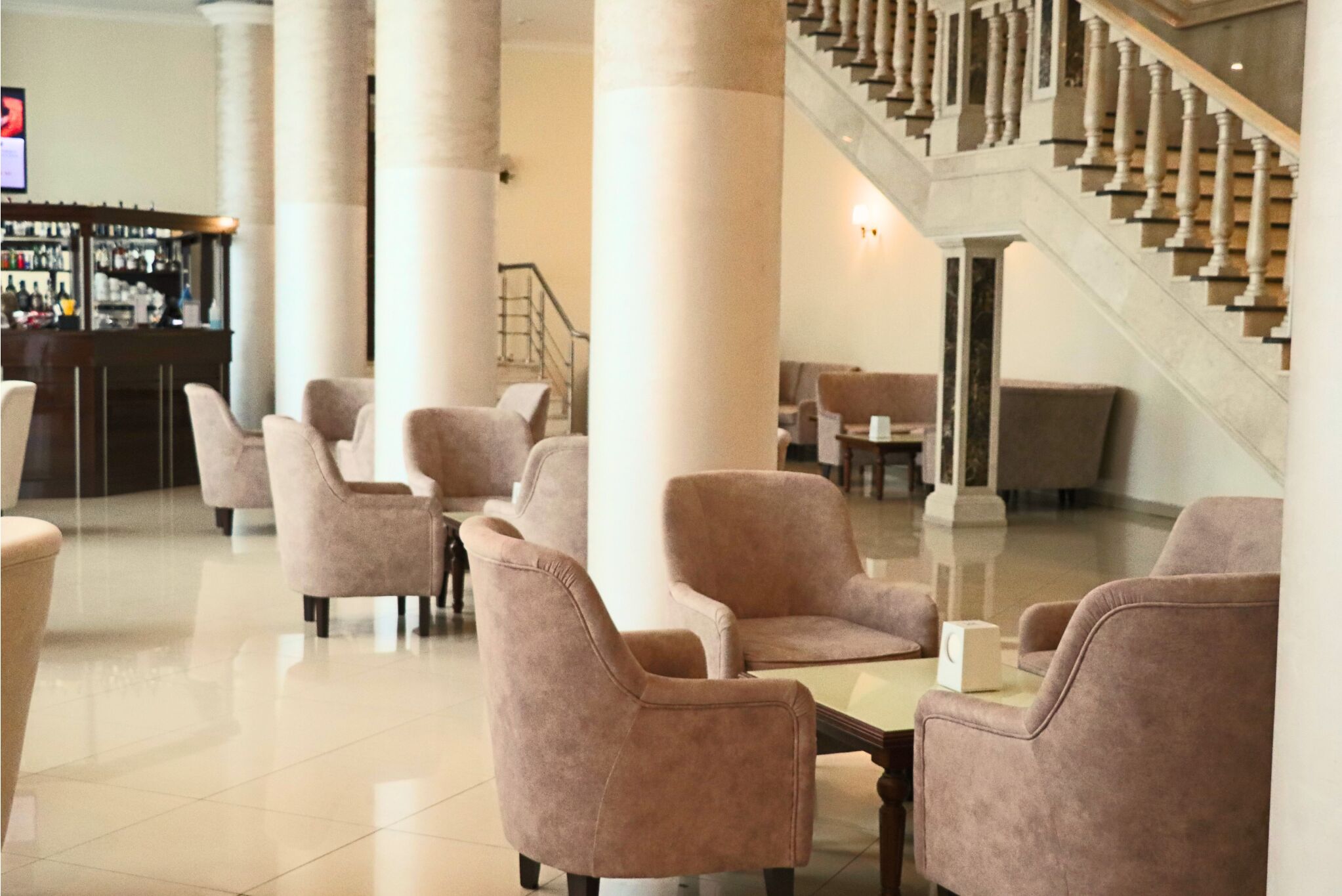 A lobby with plush seating, a staircase, and a bar area.