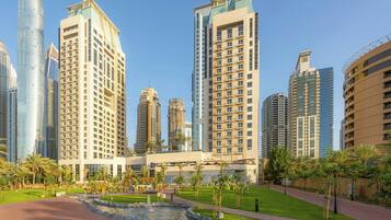 A modern hotel complex with high-rise buildings, a central courtyard with a fountain, and well-maintained greenery.