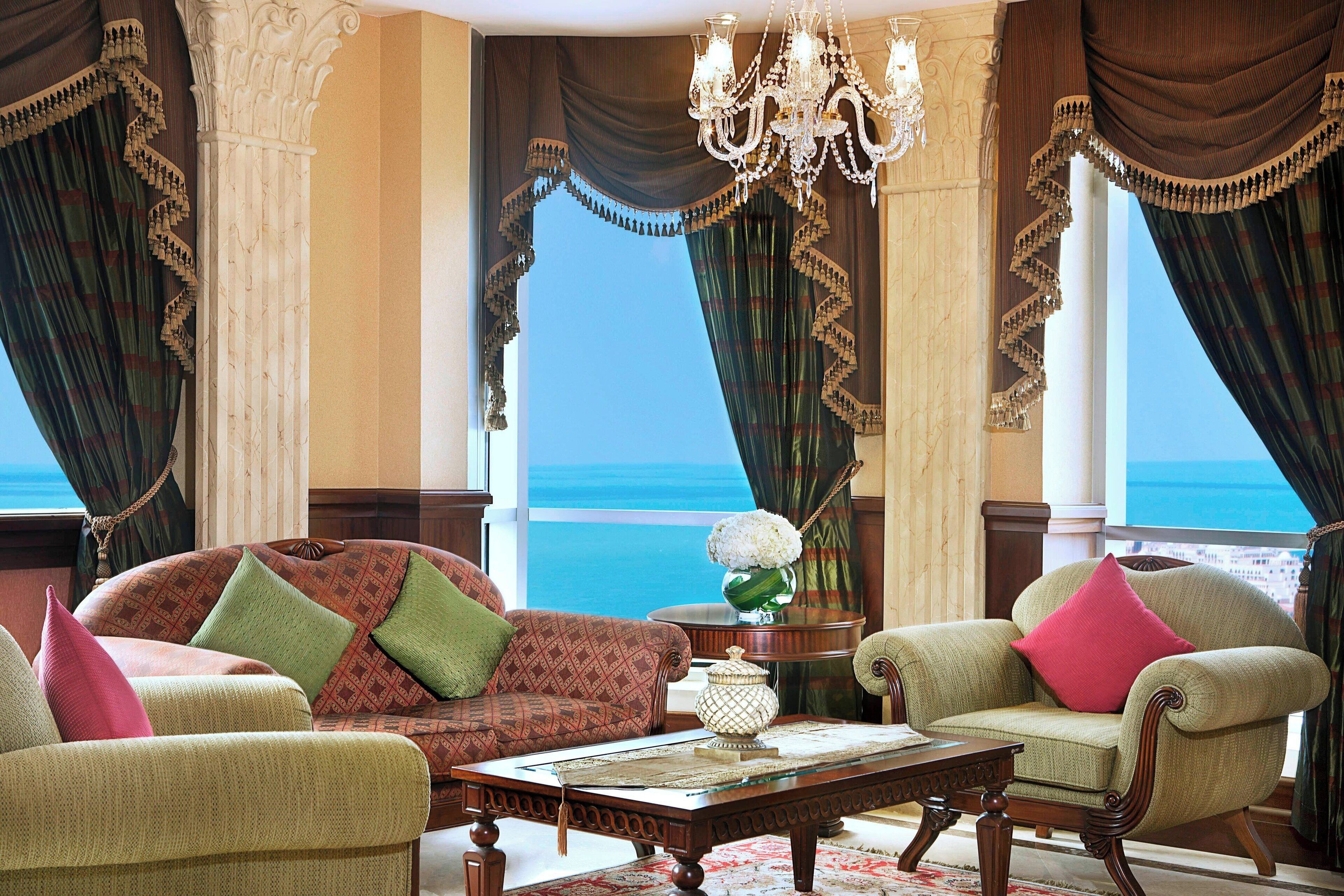 A room with a large window, a chandelier, and a view of the sea.