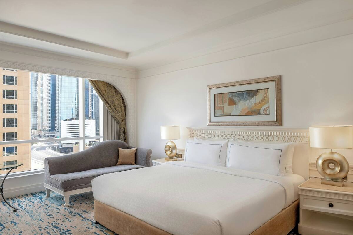 Una camera d'albergo con un letto grande, un divano, una scrivania e vista sulla città.