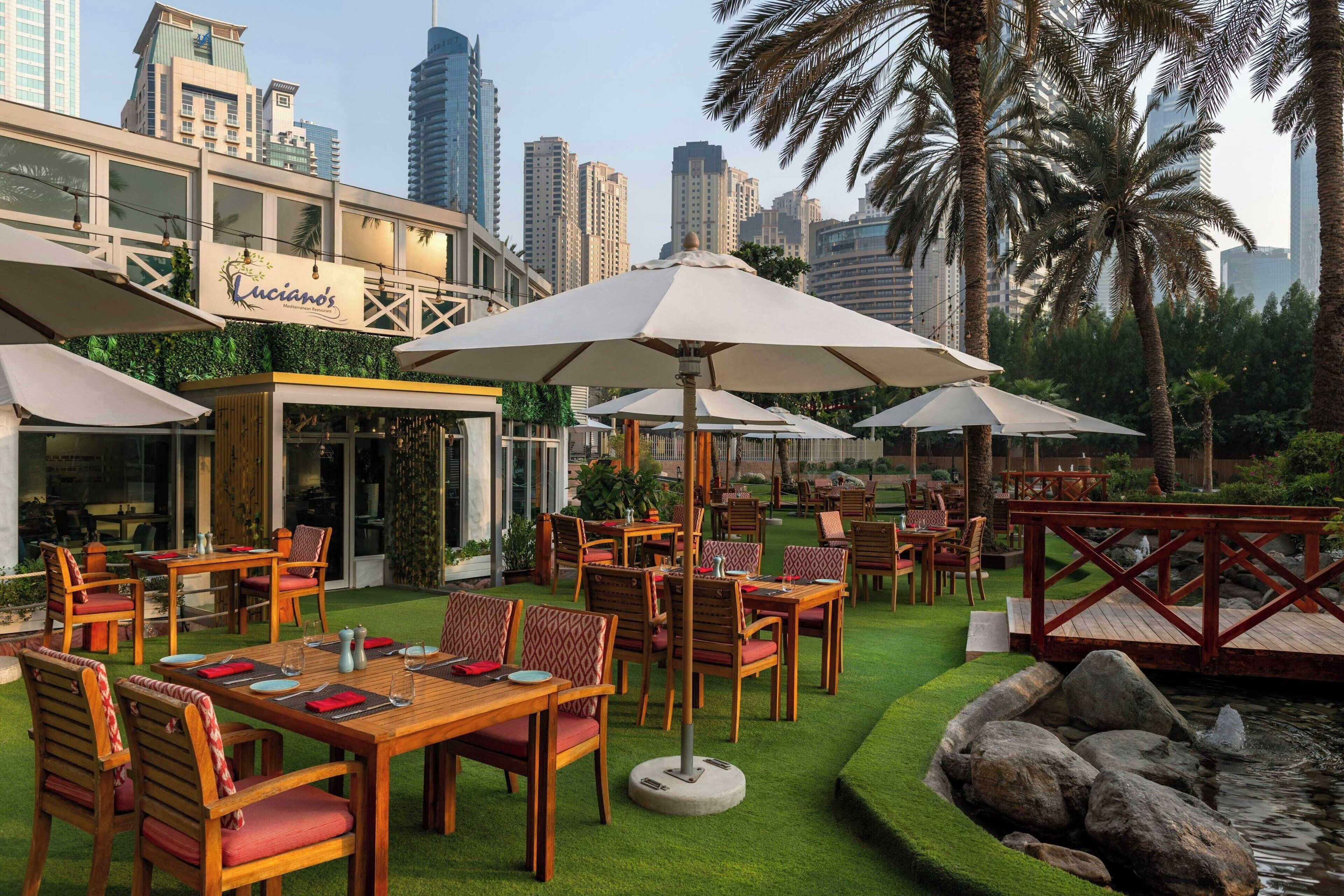 Un espace de restauration en plein air avec des tables et des chaises, des parasols et une vue sur les toits de la ville.
