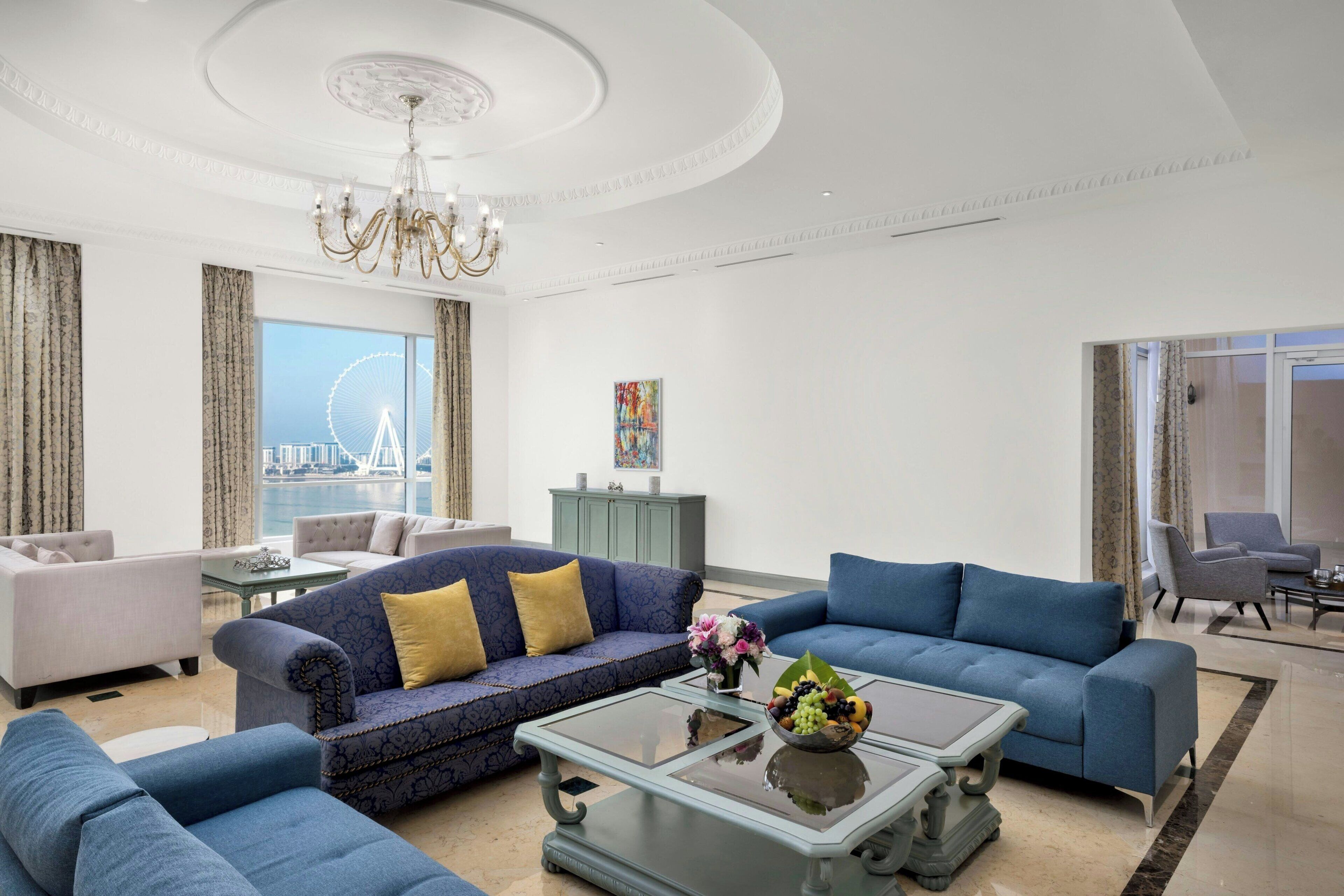 A modern living room with a large window, a chandelier, and a view of a Ferris wheel.